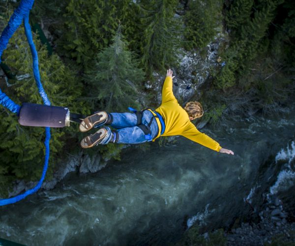 Young man bungee jumping over river.