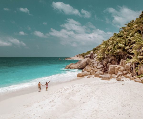 Seychelles tropical islands, Praslins Island Seychelles with couple walking on the tropical beach with palm trees and white beach blue ocean